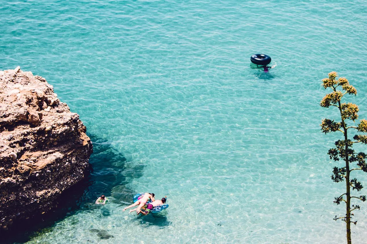 A couple of people in the water near a boat.
